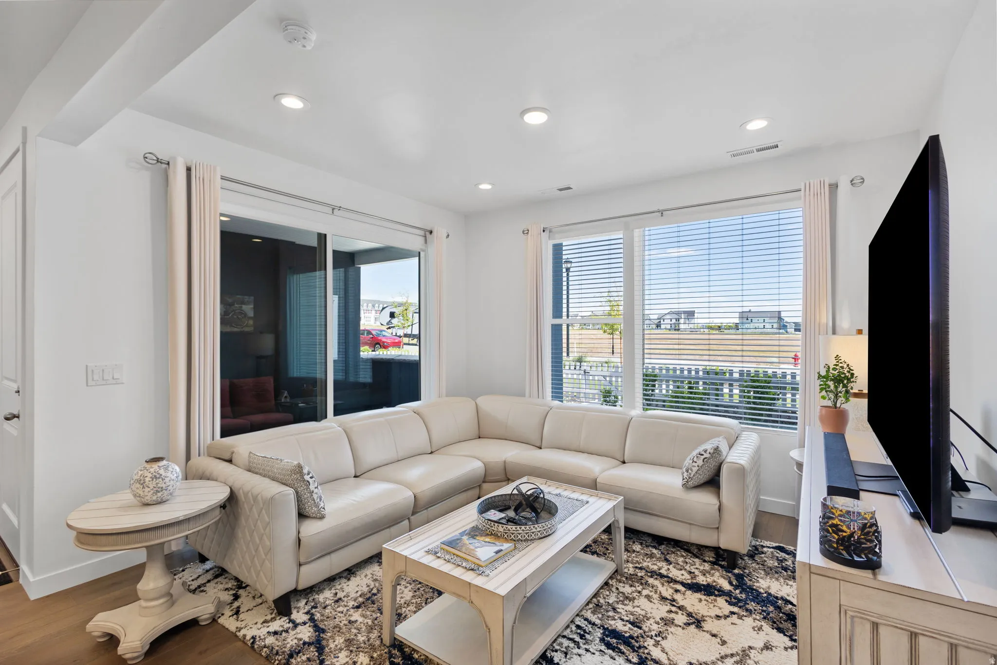 Bright living area featuring recessed lighting, LVP flooring, large windows with blinds, and a sliding glass door