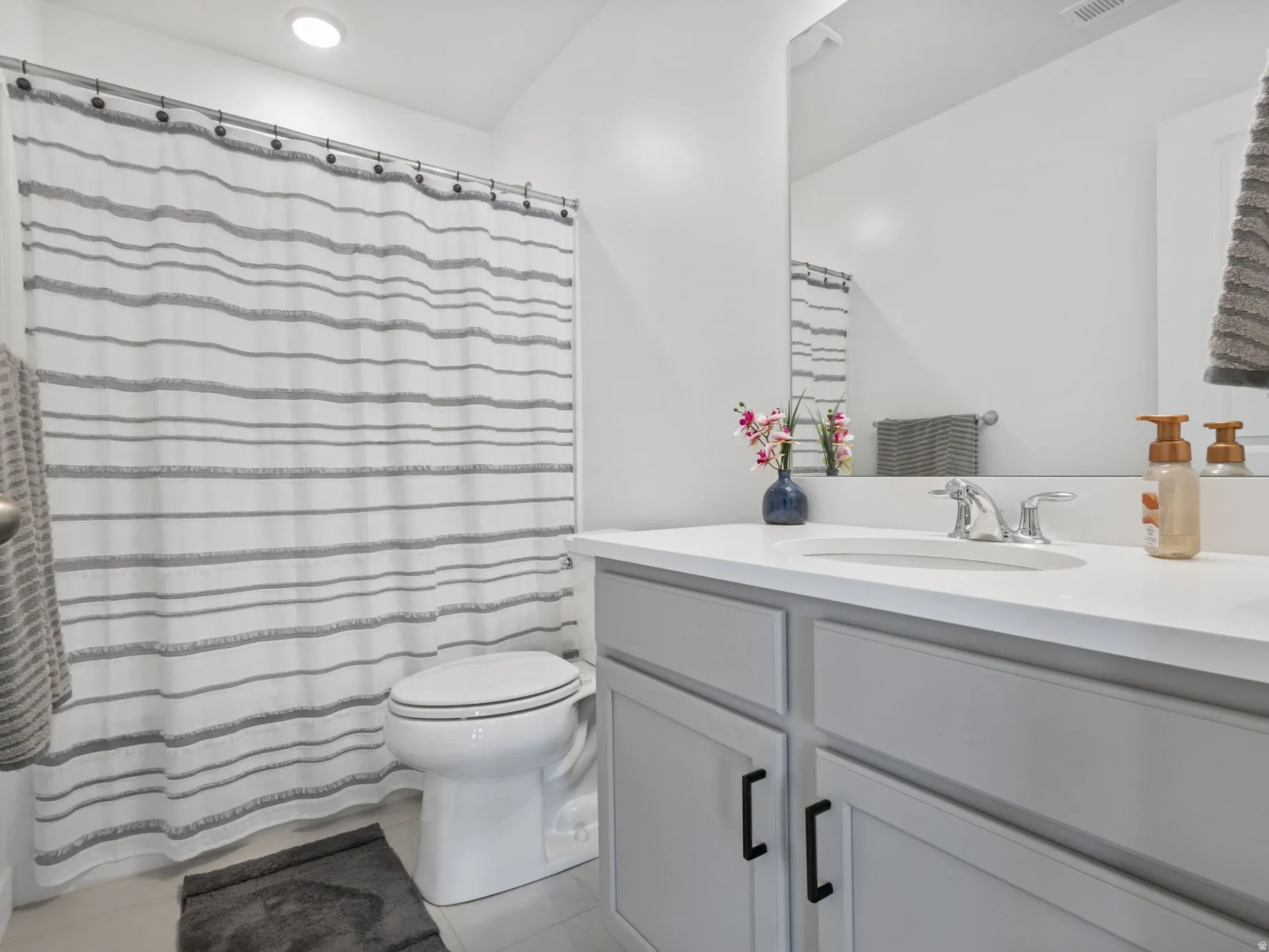 Bathroom featuring a single vanity with light gray cabinetry, a white countertop, and a chrome faucet