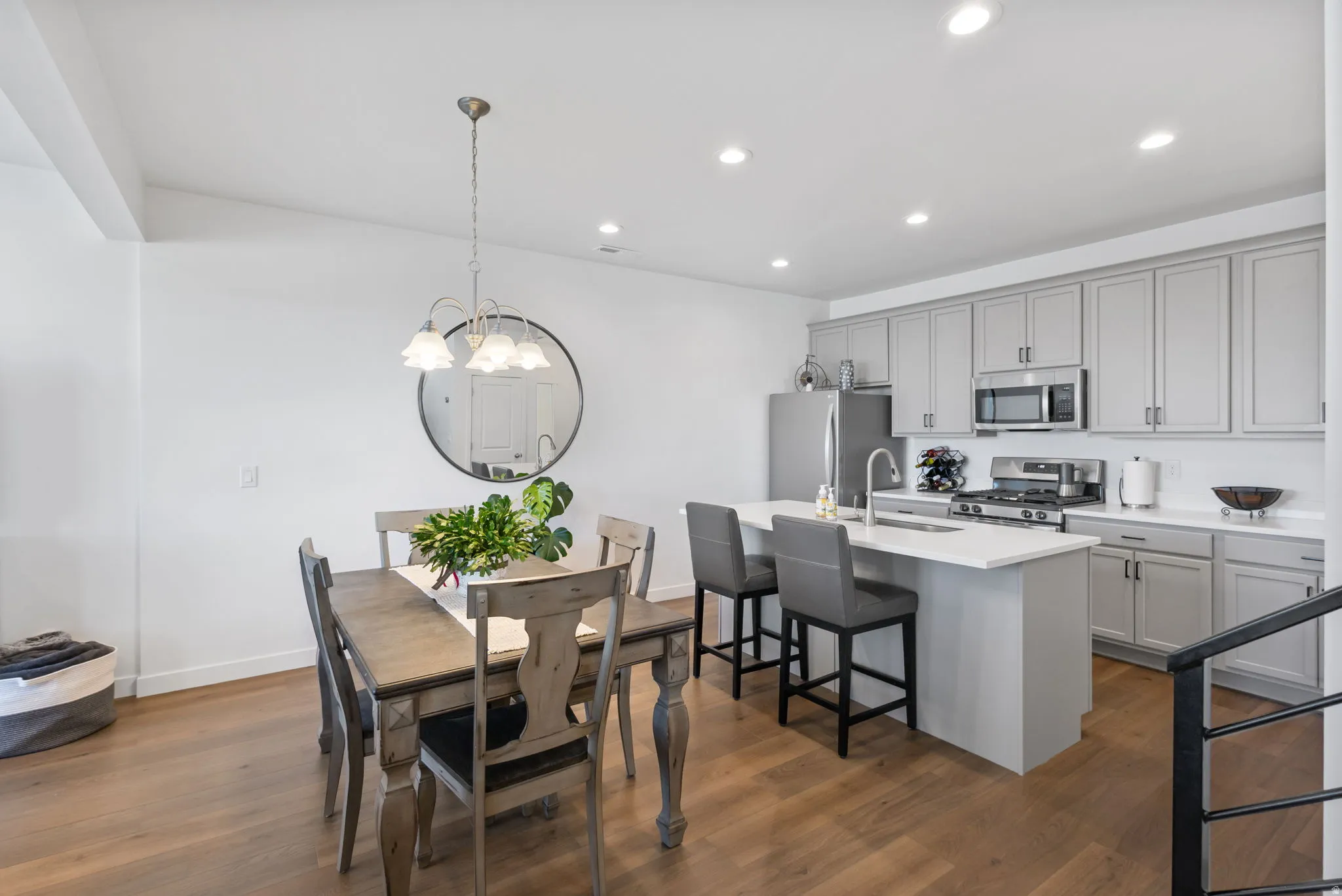 Open-concept kitchen and dining area featuring beautiful LVP flooring, quartz countertops, abundant cabinet space, recessed lighting, and a chandelier