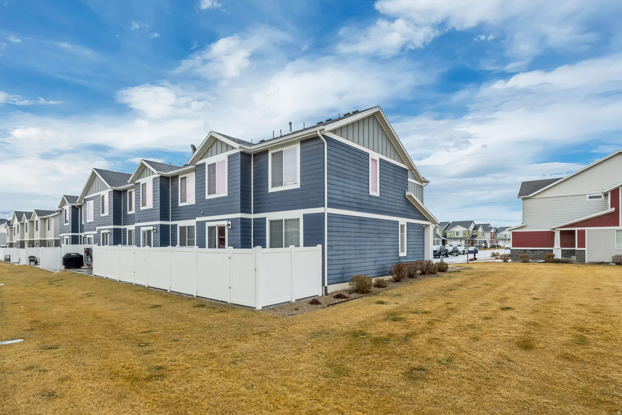 Contemporary townhome exterior featuring blue horizontal siding, white trim, and a gabled roofline