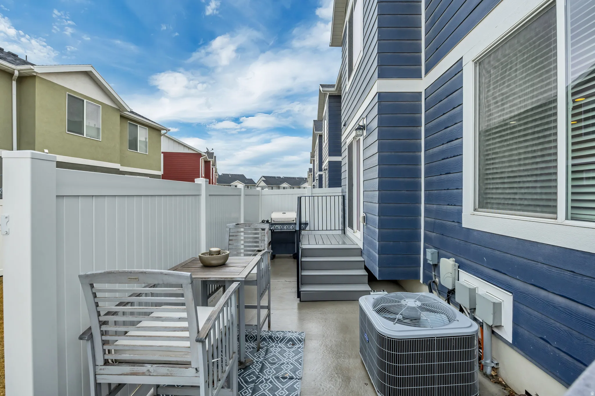 Private outdoor patio space featuring a durable gray privacy fence and a built-in deck with stairs