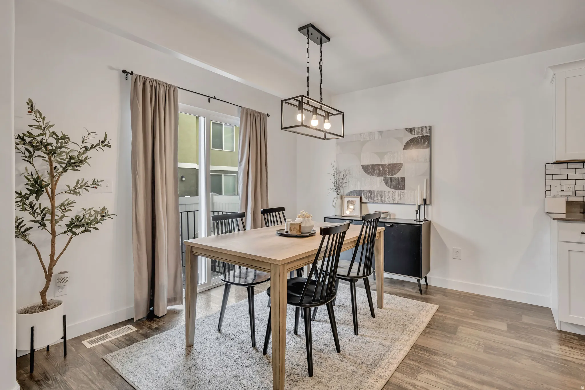 Dining area featuring wood-finish flooring, a contemporary chandelier, and a sliding glass door leading to a balcony
