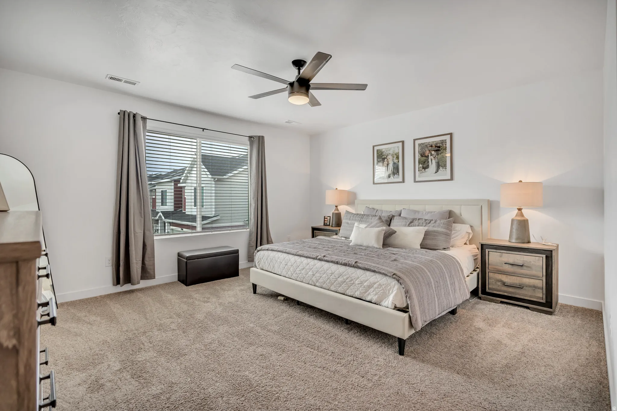 Carpeted room featuring a large window with blinds and curtains, a ceiling fan with integrated lighting, and white walls