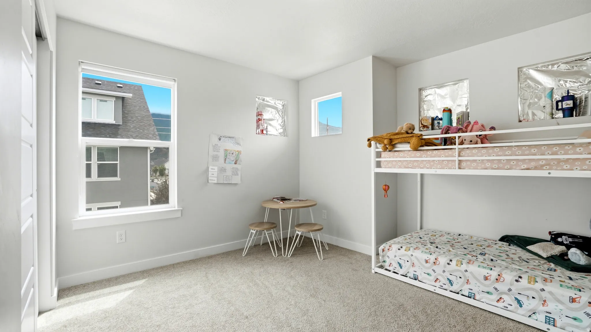 Light gray painted walls define this room featuring a large window, two smaller transom windows, and light neutral carpet flooring