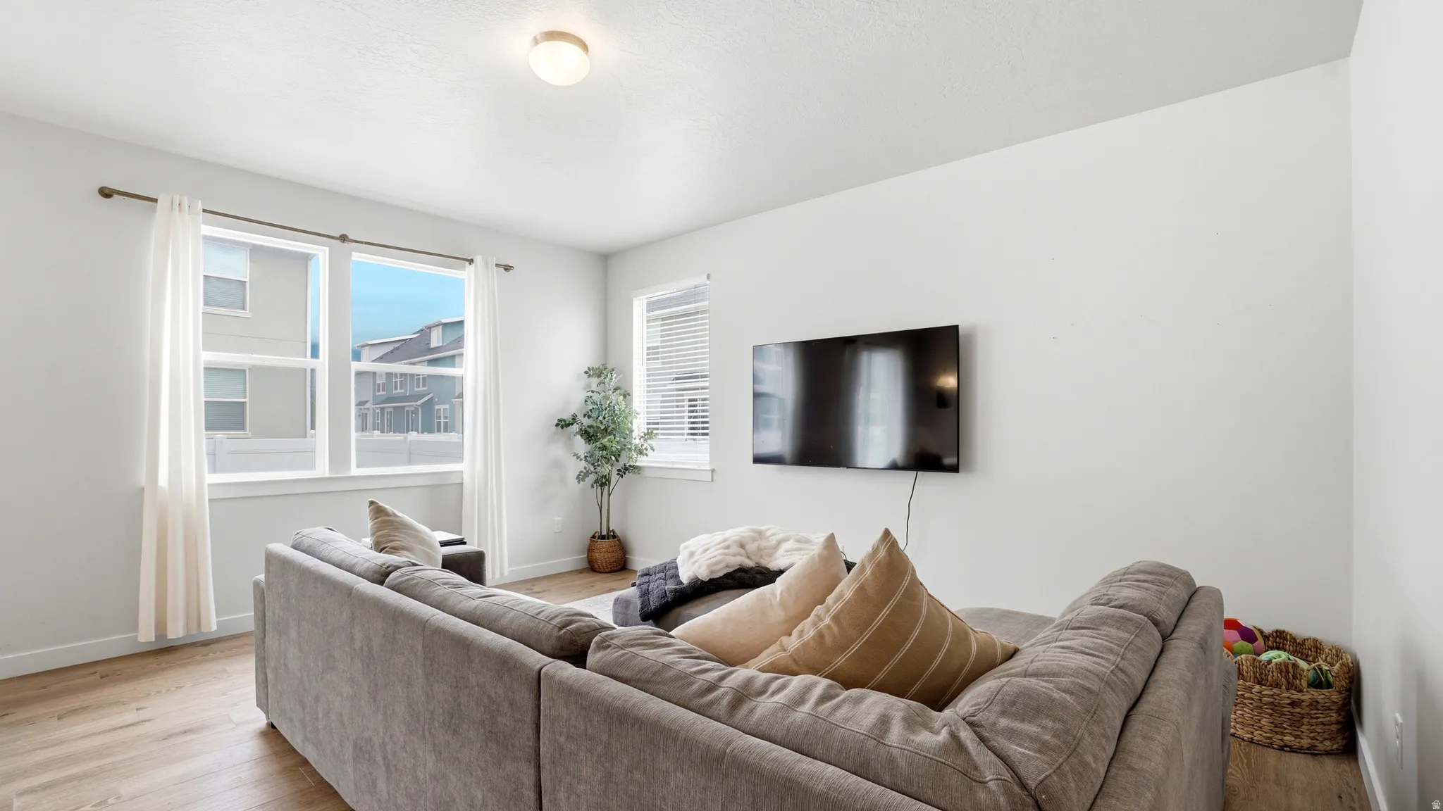 Bright living space featuring wood-finish flooring, white walls, and multiple windows