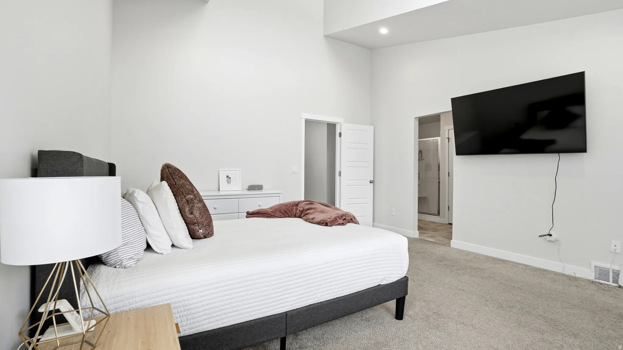 Spacious bedroom featuring vaulted ceilings, recessed lighting, and light gray wall paint
