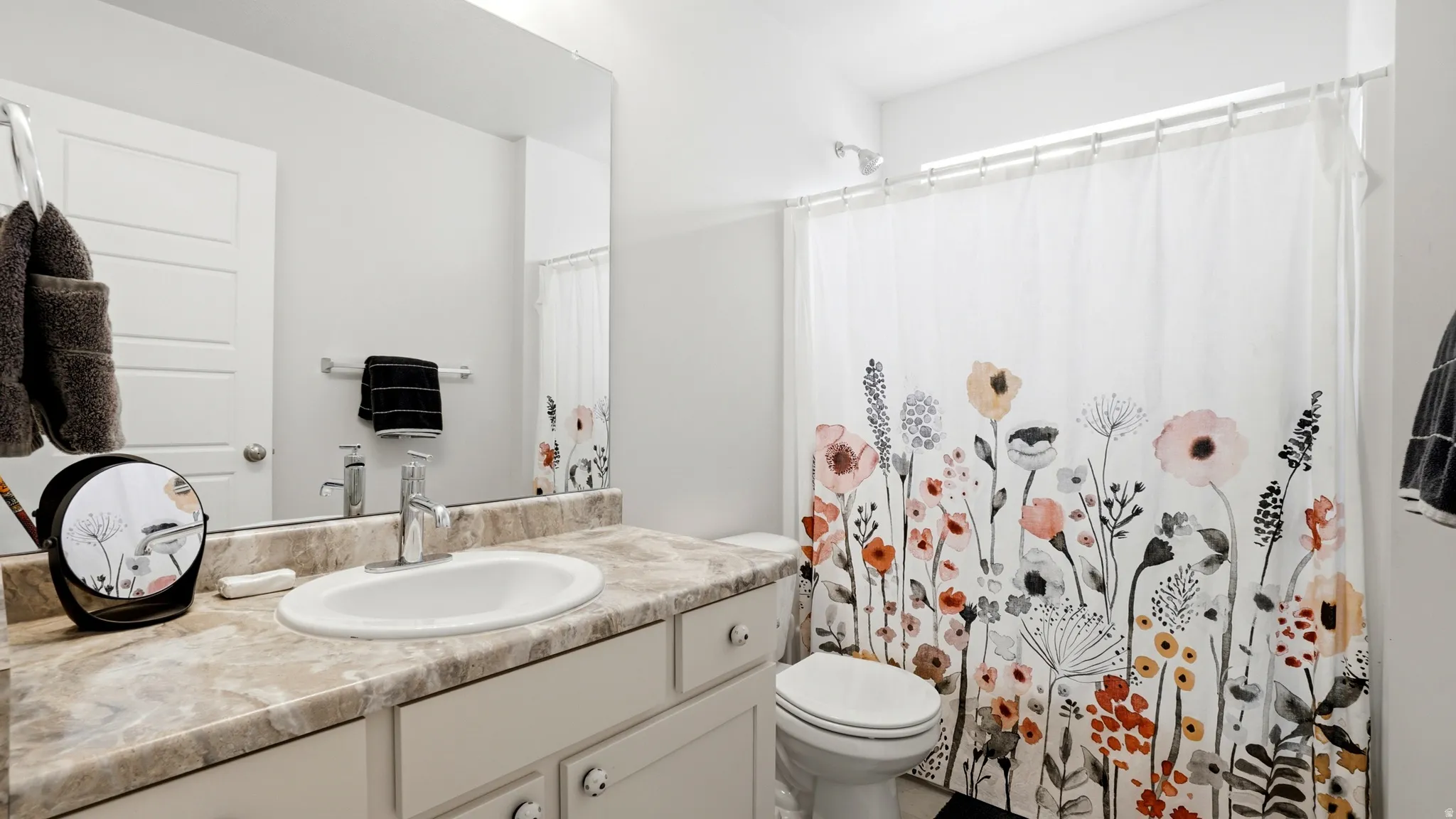 Bathroom featuring a single vanity with a laminate countertop, an undermount sink, and a large wall-mounted mirror