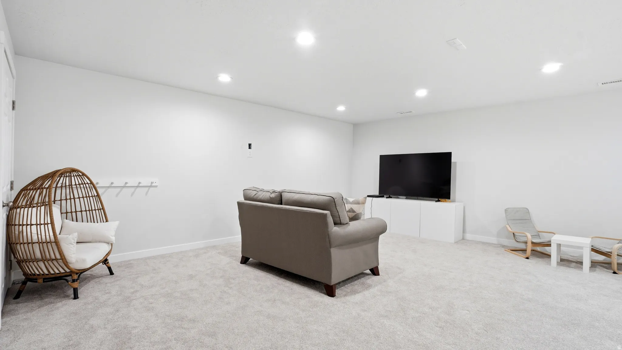 Spacious open room featuring light-colored carpeting, white walls, and recessed lighting