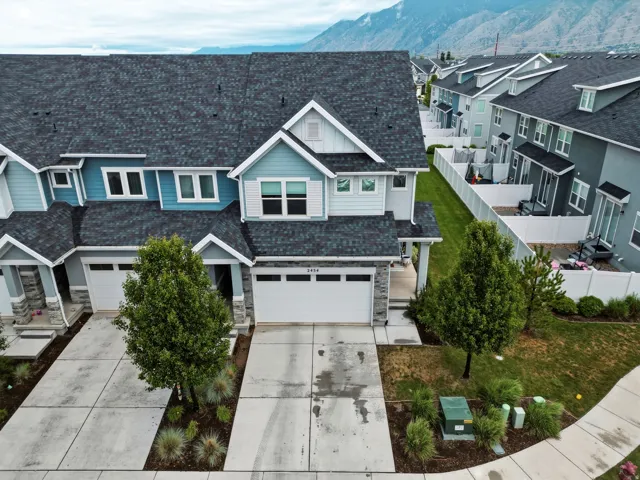 Contemporary townhome exterior featuring light blue siding, stone accents, a dark shingle roof, and an attached two-car garage