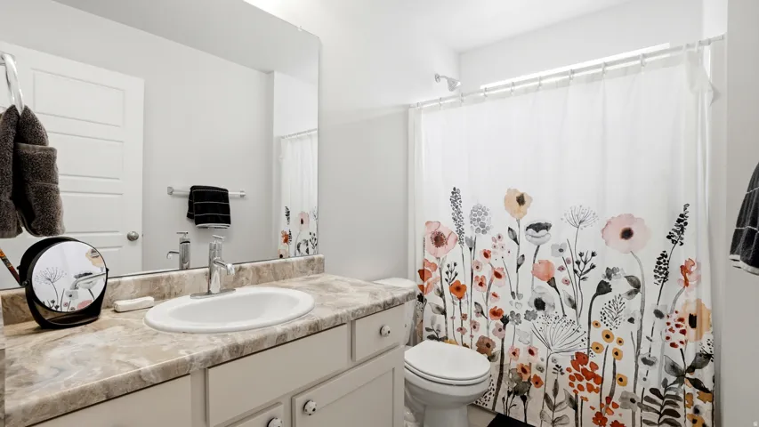 Bathroom featuring a single vanity with a laminate countertop, an undermount sink, and a large wall-mounted mirror