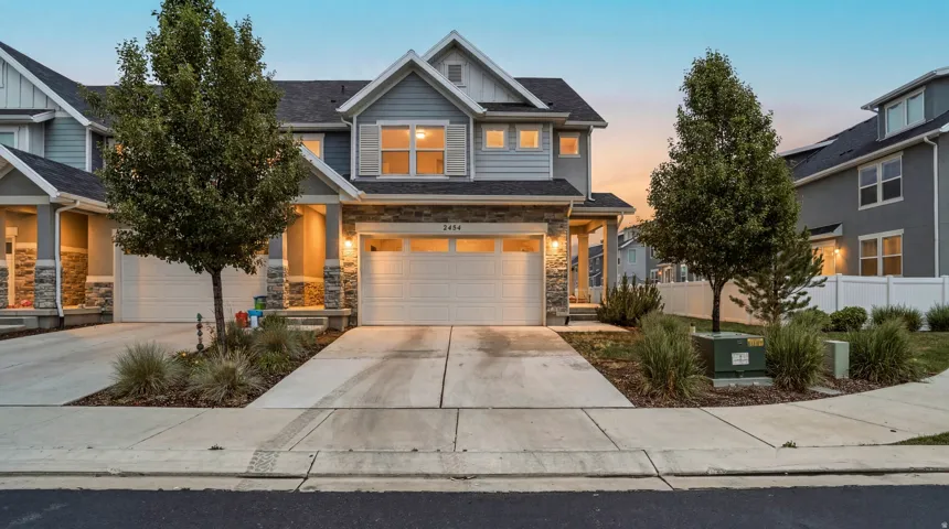 Multi-level residence featuring light blue siding, stone facade accents, and a two-car garage