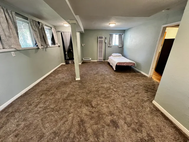 Spacious room featuring textured brown carpeting and light green painted walls
