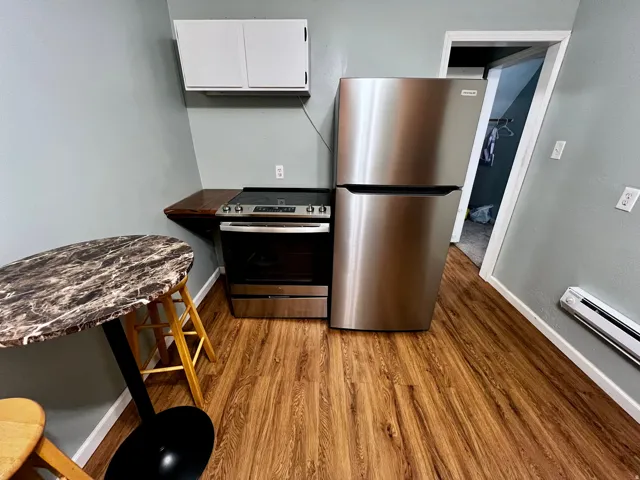 Compact kitchen area featuring stainless steel appliances, wood-finish flooring, and white wall cabinetry
