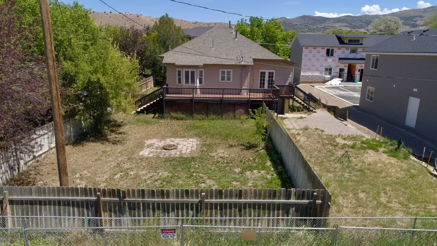 Spacious backyard featuring a brick patio area, wood fencing, mature trees, and a multi-level wood deck with stairs