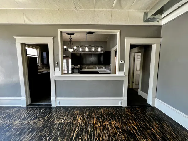 Kitchen pass-through opening to a living area with dark wood-finish flooring
