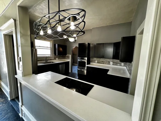 Kitchen featuring a contemporary chandelier, white countertops, dark cabinetry, and a built-in stovetop