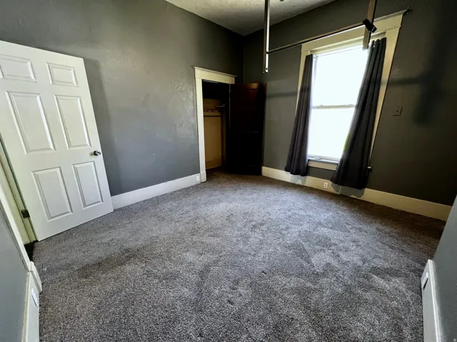 Carpeted room featuring a white paneled door, dark gray walls, and white baseboards