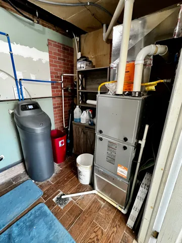 Modern furnace system with visible ductwork, a water softener unit, and wood-finish flooring