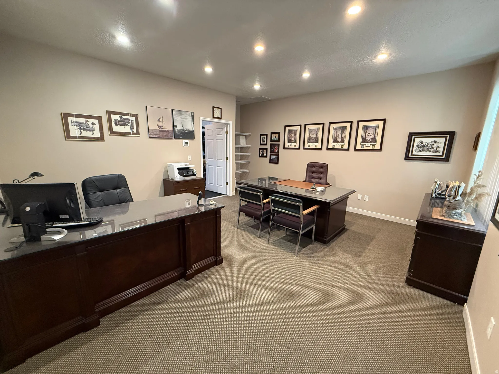 Spacious office area featuring recessed lighting, neutral wall tones, and patterned carpet flooring