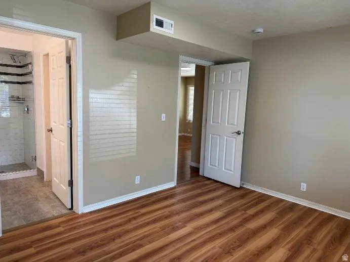 Bedroom with wood-finish flooring, neutral wall tones, and white trim