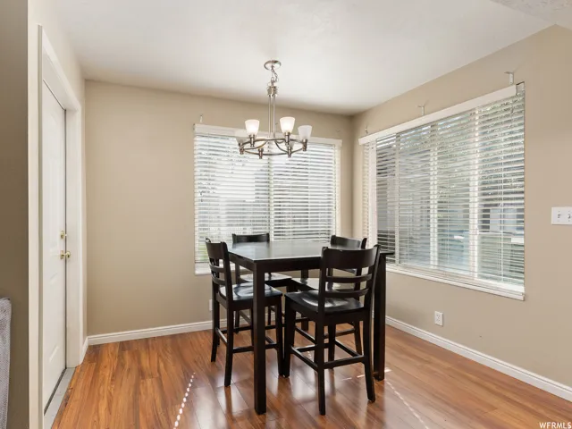 Dining area featuring wood-finish flooring, neutral wall paint, and multiple windows with blinds