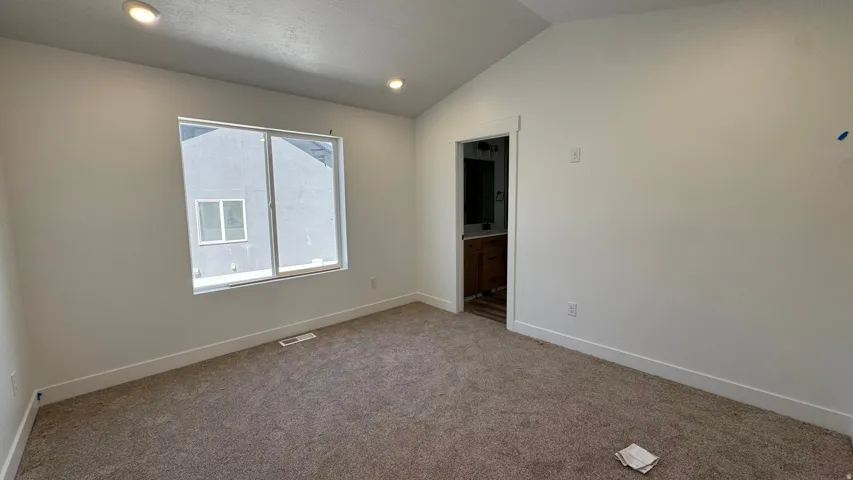Carpeted flooring, vaulted ceiling, recessed lighting, and a large window
