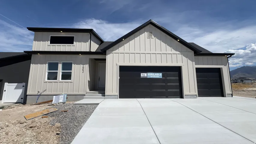 Modern exterior featuring board and batten siding, a black shingle roof, dark-framed windows, and a concrete driveway