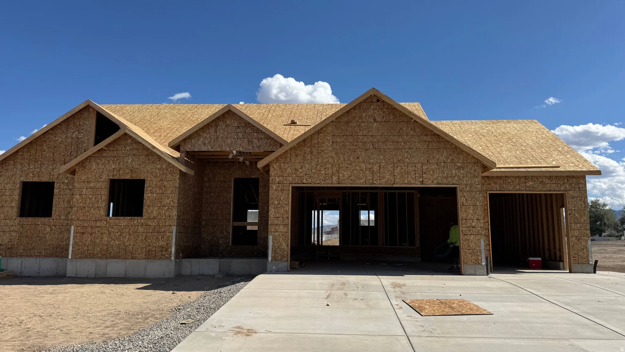 New construction home featuring sheathed exterior walls, a two-car garage opening, a single-car garage opening, and a concrete driveway