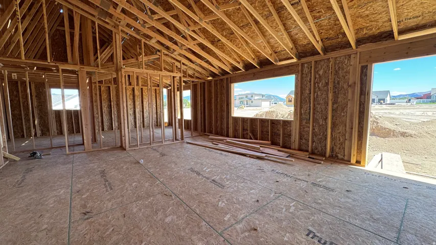 Spacious interior framing with visible roof trusses, multiple window openings, and an exterior door opening