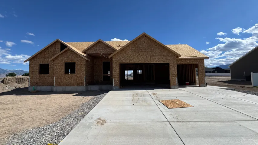 New construction home featuring a three-car garage, concrete driveway, and mountain backdrop