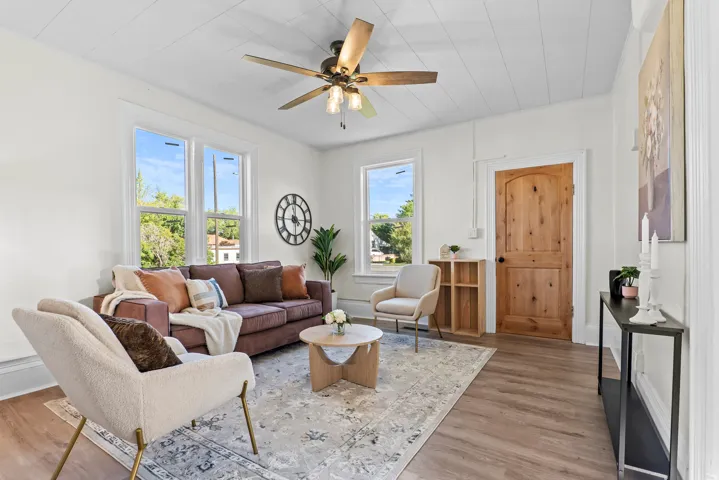 Bright living area featuring wood-finish flooring, white walls, and a paneled ceiling