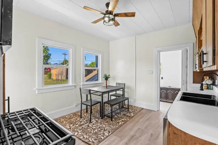 Kitchen featuring wood-finish flooring, white cabinetry, a built-in gas range, dual black sinks, and a ceiling fan
