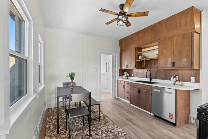 Kitchen featuring wood-finish cabinetry, white countertops, a stainless steel dishwasher, and a black faucet