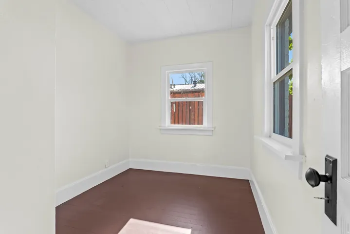 Compact interior room featuring light-colored walls, dark wood-finish flooring, and white baseboards