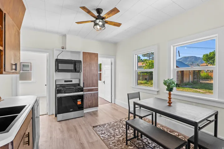 Kitchen and dining area featuring wood-finish flooring, white walls, and a ceiling fan with integrated lighting