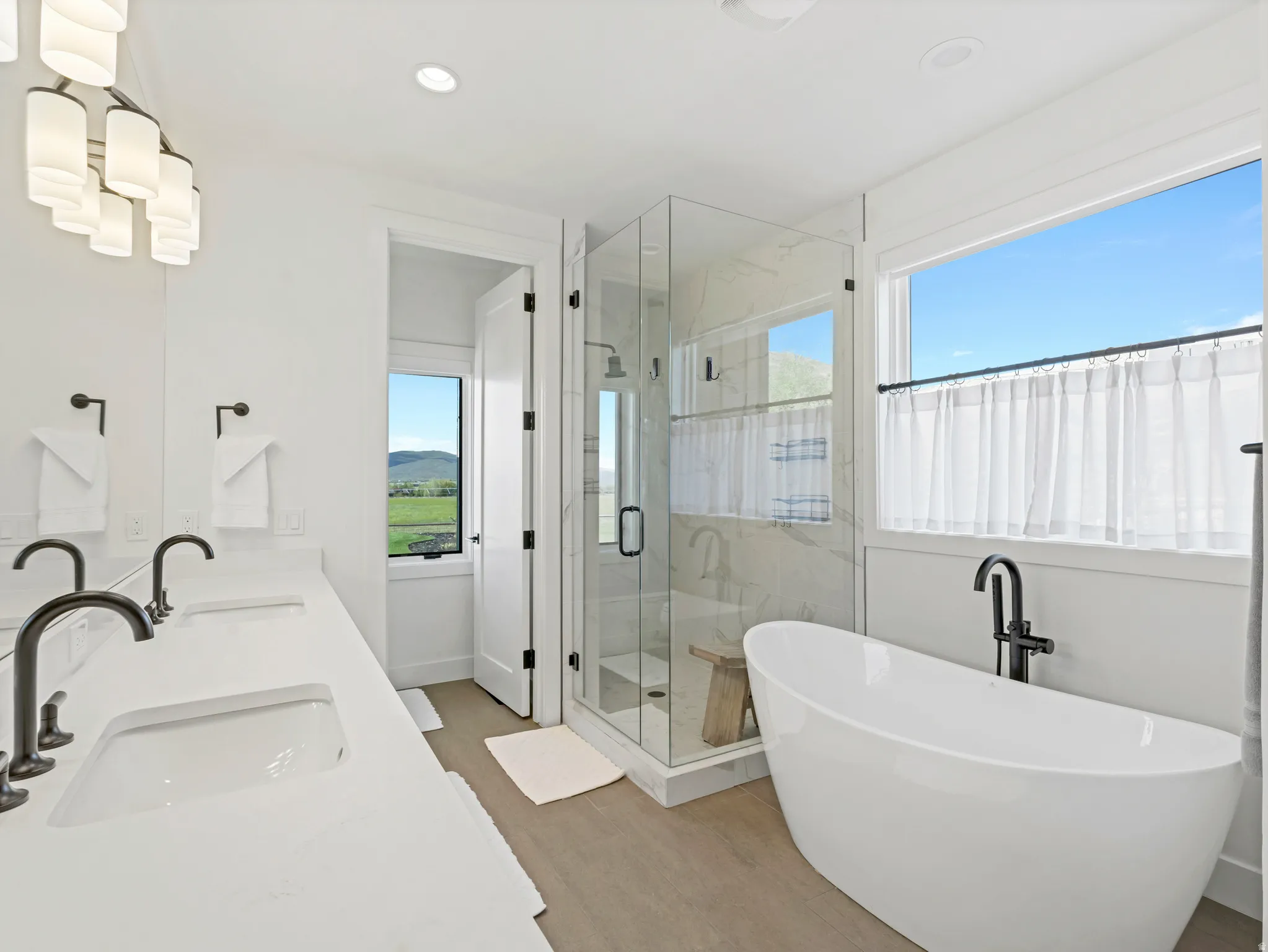 Contemporary bathroom featuring a freestanding soaking tub with floor-mounted fixture, a glass-enclosed shower with tiled walls, and a double vanity with undermount sinks and dark bronze fixtures