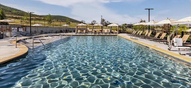 Resort-style pool with integrated spa, surrounded by lounge seating and shaded cabanas