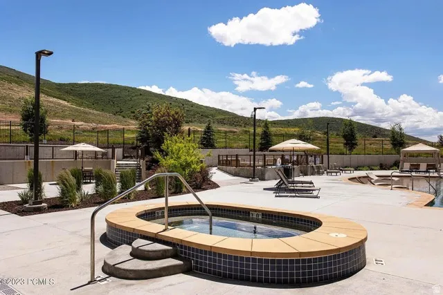 Outdoor spa with tiled exterior and concrete steps, surrounded by a concrete patio