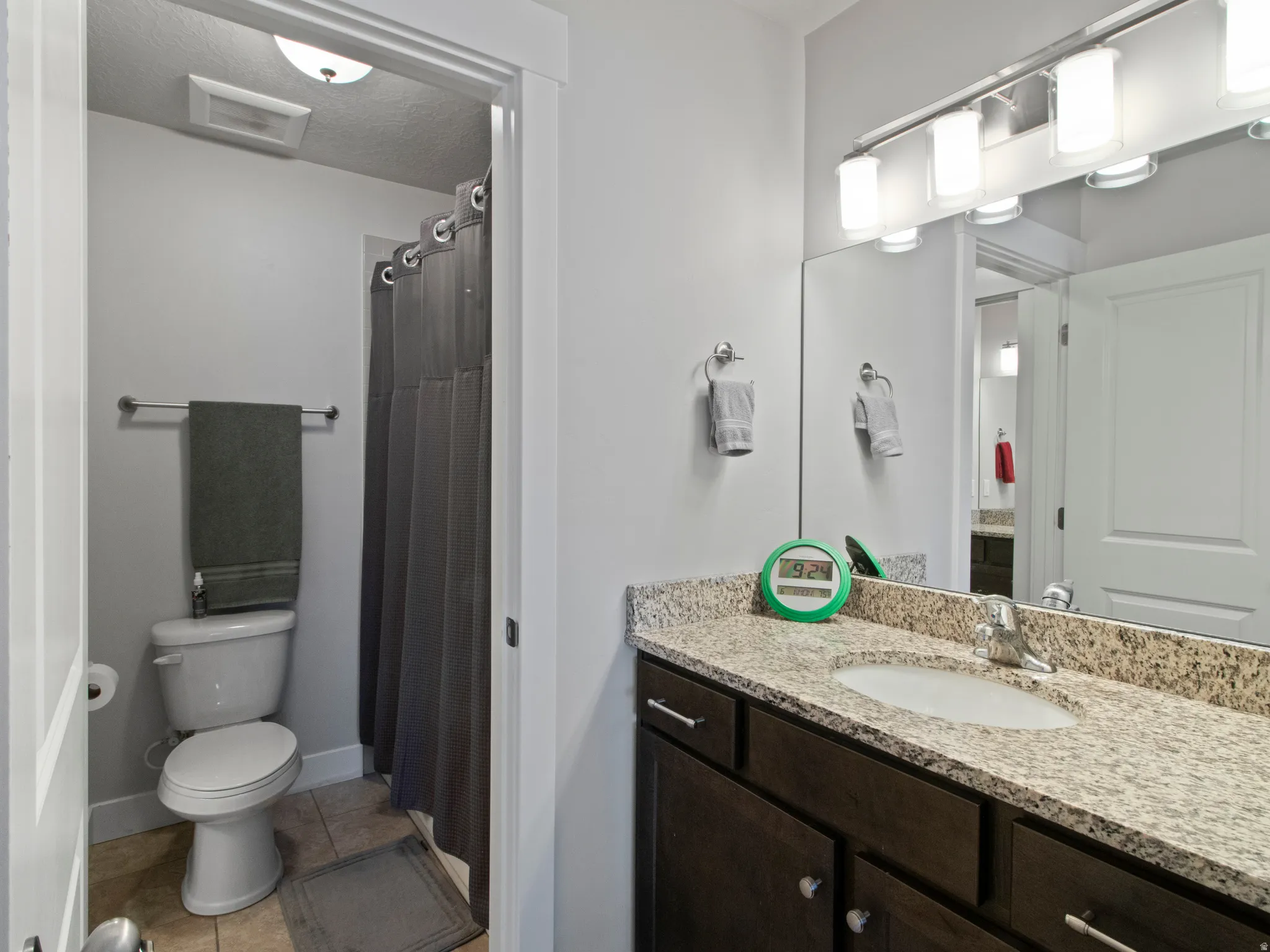 Bathroom featuring a single vanity with dark wood-finish cabinetry and a light speckled countertop