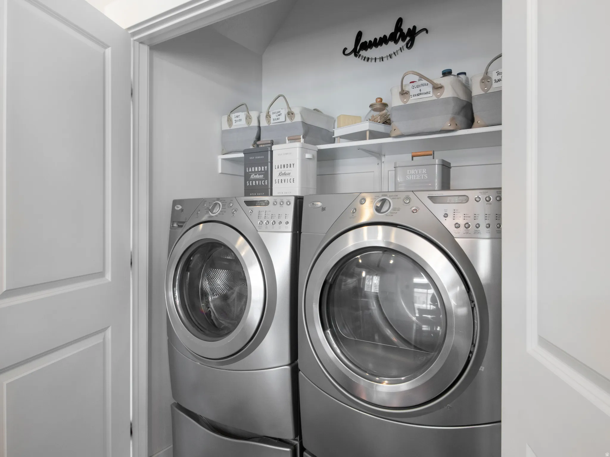 Dedicated laundry closet featuring a stacked washer and dryer, white shelving, and a painted finish