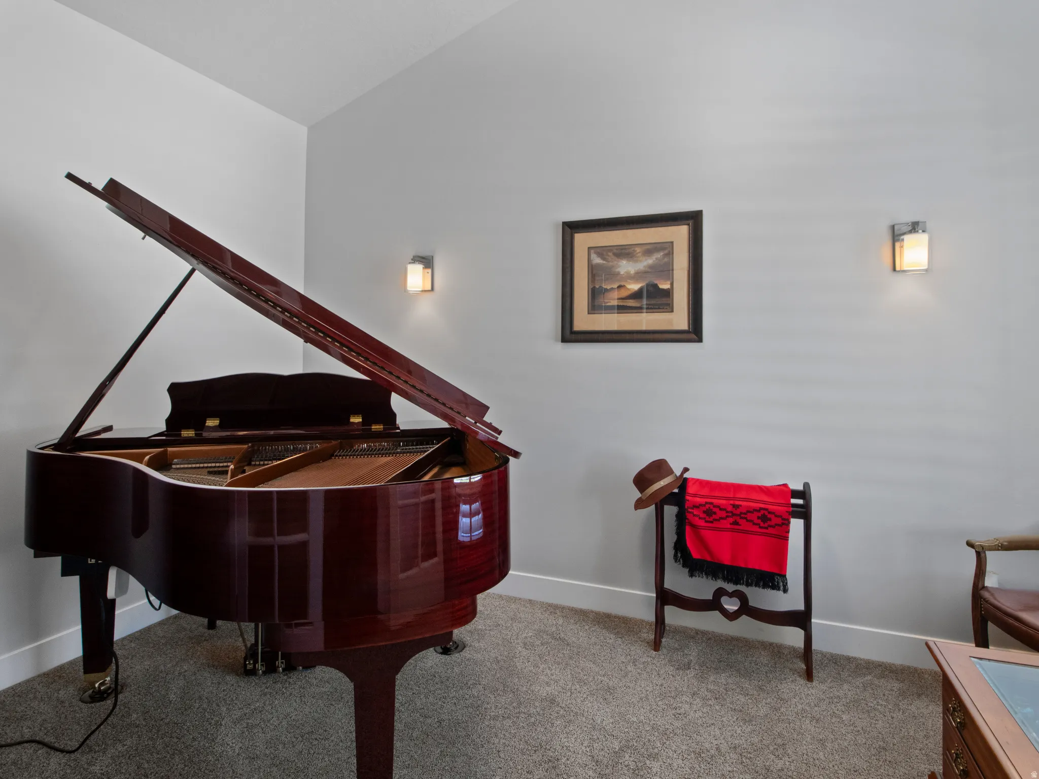Carpeted room featuring light gray walls, white baseboards, and two wall-mounted sconces providing ambient lighting