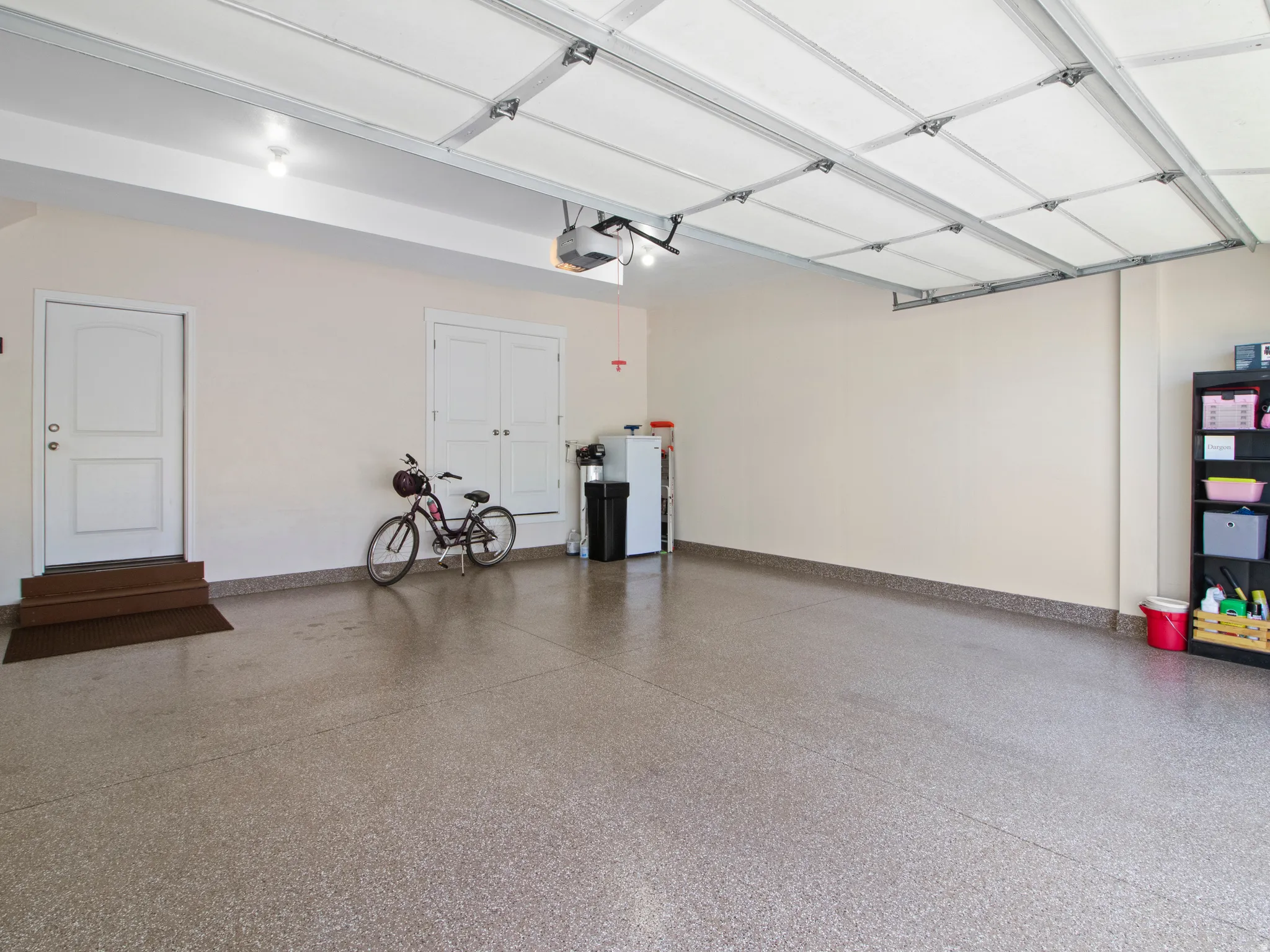 Spacious garage featuring a durable epoxy floor coating, painted walls, and an automatic garage door opener