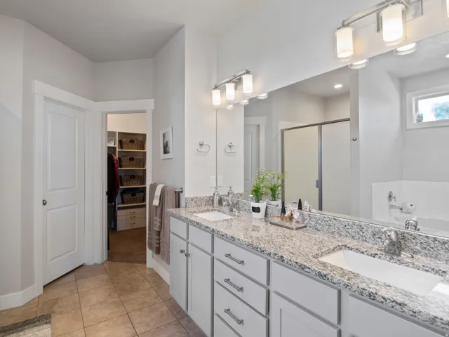 Bathroom featuring a dual vanity with granite-look countertops and undermount sinks