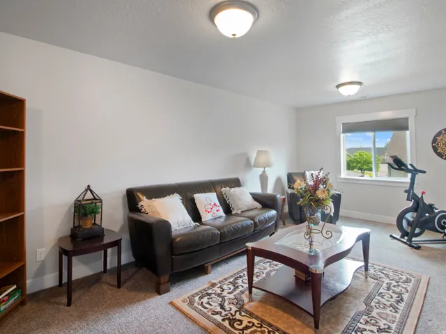 Carpeted room with a large window, providing natural light and a distant green landscape