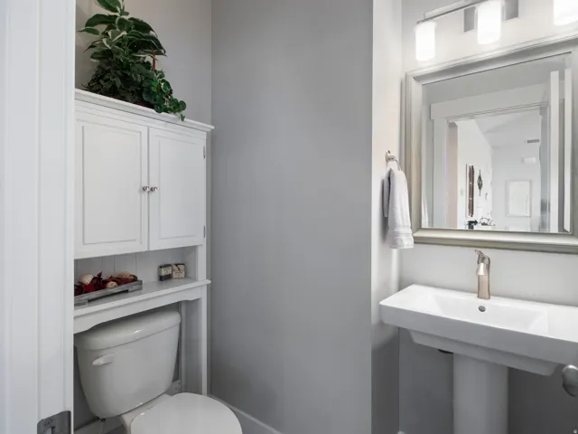 White pedestal sink with a brushed nickel faucet and a framed mirror