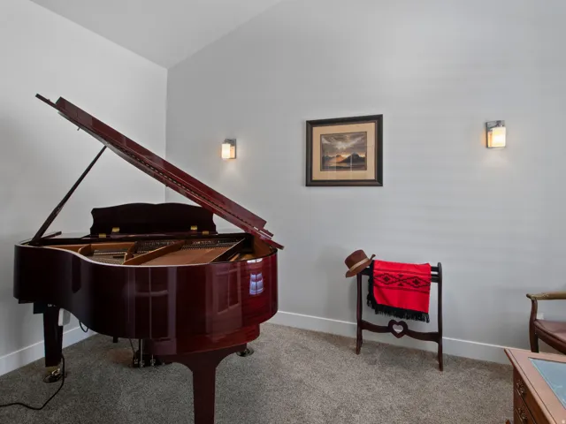 Carpeted room featuring light gray walls, white baseboards, and two wall-mounted sconces providing ambient lighting