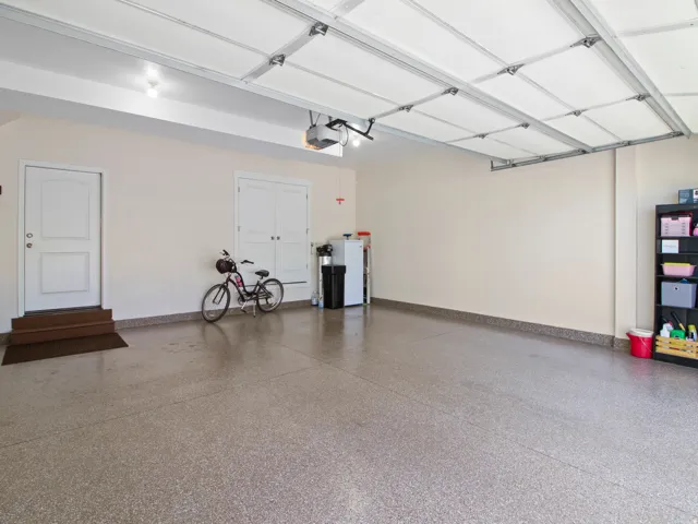Spacious garage featuring a durable epoxy floor coating, painted walls, and an automatic garage door opener