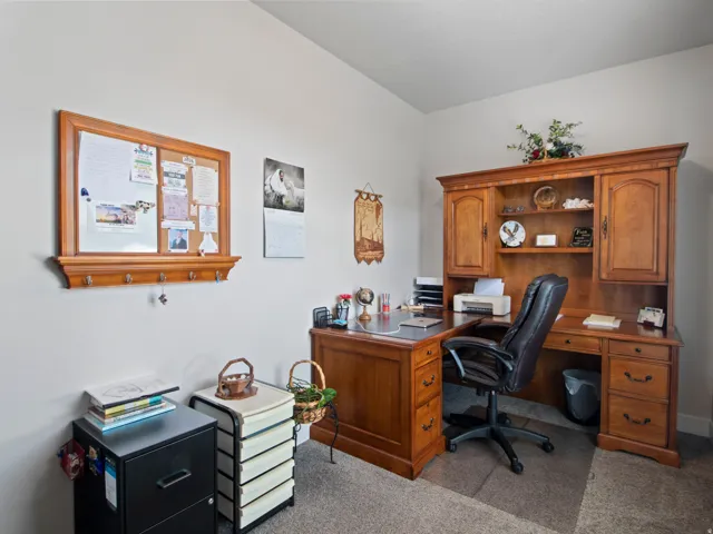 Dedicated office space featuring a built-in wood-finish desk with hutch, integrated shelving, and cabinet storage