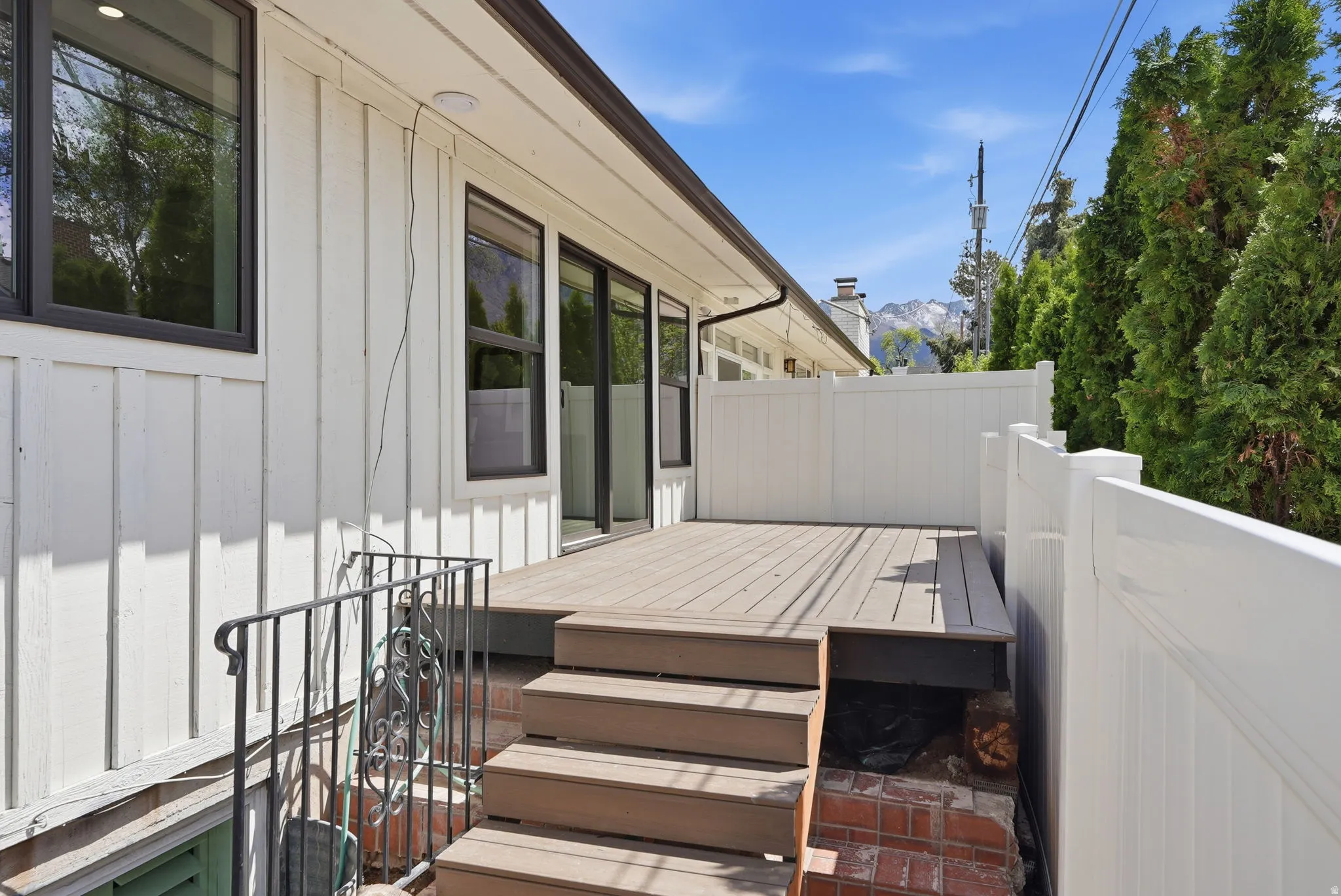 Outdoor deck with multi-level steps, white vinyl fencing, and board and batten siding