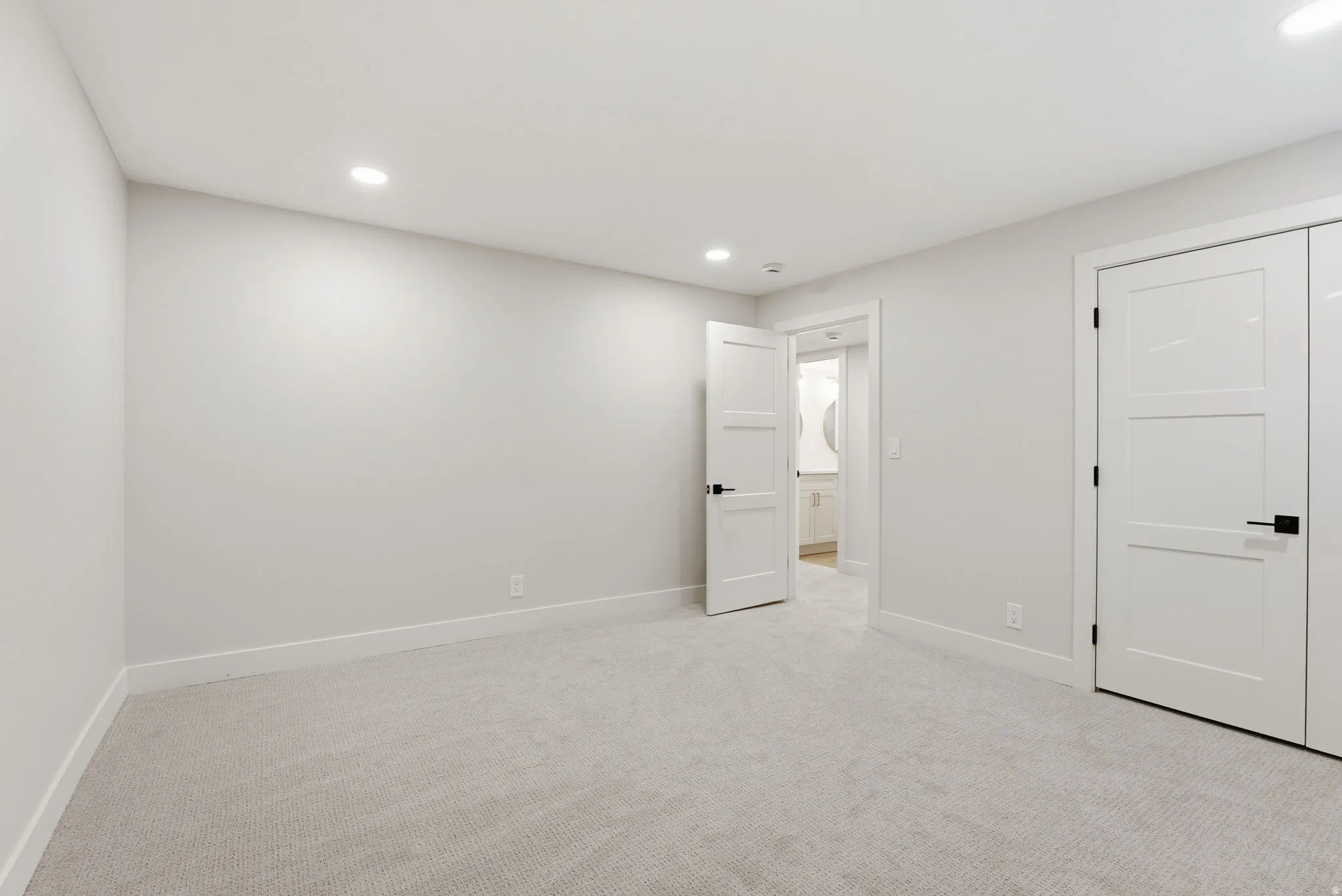 Neutral-toned room featuring light gray carpeting, crisp white walls, and recessed lighting